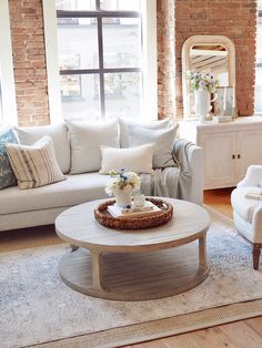 a living room with white furniture and brick walls