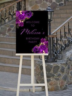 a welcome sign with purple flowers on it in front of some stairs and stone steps