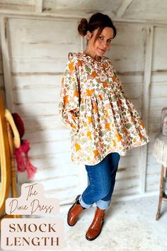 Woman standing wearing a floral print dress with jeans and brown boots