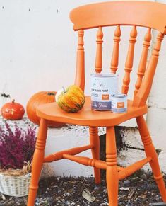 an orange chair next to a white wall with pumpkins and paint on the seat