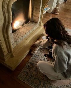 a woman kneeling down next to a fire place