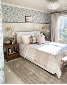 a bedroom with blue and white floral wallpaper, a large bed in the center