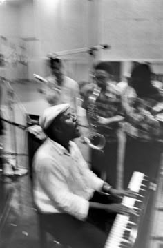 a man sitting at a piano in front of a group of people playing musical instruments