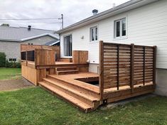 a wooden deck in front of a house with stairs leading up to the back door