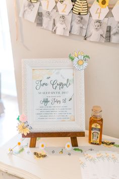 a white table topped with a framed sign next to honey bottles