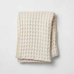 a white knitted blanket folded on top of each other in front of a white wall