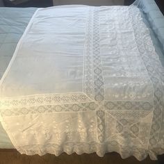 the bed is made with white linens and crocheted lace on it's edges