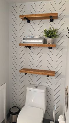 a white toilet sitting in a bathroom next to two wooden shelves