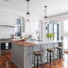 a large kitchen with an island in the middle and three stools at the counter