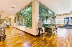 a large living room with wooden floors and lots of plants in the window sill