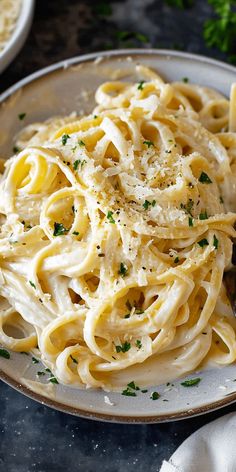 a plate full of pasta with parmesan cheese and parsley on the side