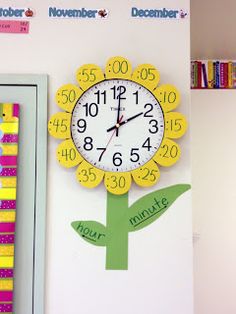 there is a clock on the wall next to a book shelf with books and magnets