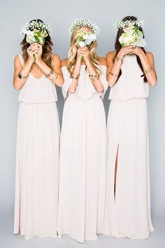 three beautiful women in white dresses holding flowers