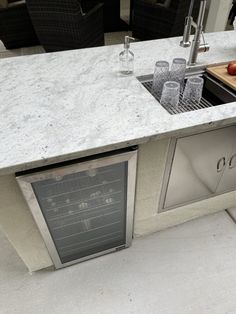 an outdoor kitchen with marble counter tops and stainless steel sink