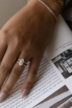 a woman's hand on top of an open book with a diamond ring in it