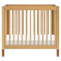 a wooden crib with white sheets in it