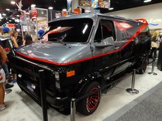 a black truck with red trim parked in front of a group of people looking at it