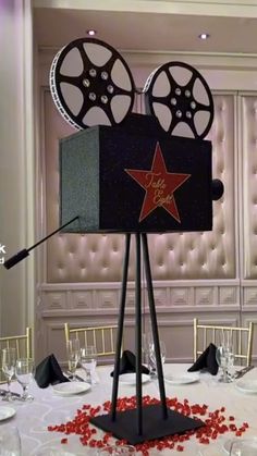 a table set up for a movie themed event with red rose petals on the table