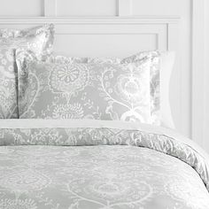 a bed with pink comforter and pillows on top of the headboard in front of a white wall