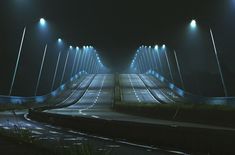 an empty street at night with lights shining on the road and overpasss in the background