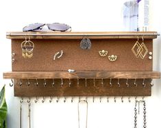 a wooden shelf with several pairs of earrings hanging from it's sides and hooks attached to the wall