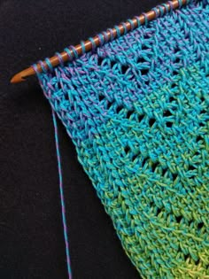 a close up of a crocheted piece of cloth with a knitting needle next to it