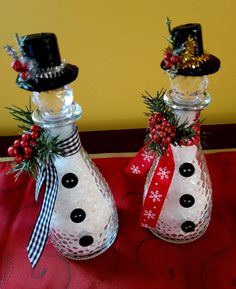 two glass vases decorated with snowmen and christmas decorations on a red table cloth