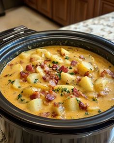 a crock pot filled with potatoes and bacon on top of a kitchen countertop