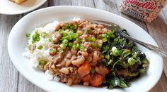 a white plate topped with rice, beans and greens next to a bag of peanuts