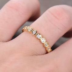 a person's hand with a gold ring on top of their finger and three diamonds in the middle