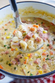 a spoon full of soup with ham and potatoes