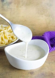 a white bowl filled with macaroni and cheese being drizzled over it