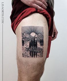 a man's leg with a tattoo of trees and mountains in the water on it