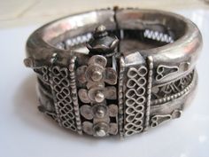 A beautifully crafted silver bracelet from India from the first part of the 20th century. The body is made up of handmade two tubes of silver with a filigree middle. The front of the bracelet is ornately decorated with motifs that are echoed on the back. The hinge for this beautiful bracelet has a wooden pin as is often the case in these early bracelets. The clasp is a screw type and the top is shaped like a flower. It works well.  The bracelet has some unevenness a few bumps and scratches, but Kuchi Jewelry, Indian Jewelry Earrings, Antique Silver Jewelry, Gold And Silver Bracelets, Bohemian Bracelets, Jewelry Indian, The 20th Century, Crafted Jewelry, Ethnic Jewelry