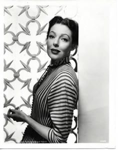 black and white photograph of a woman holding something in her hand with scissors on the wall behind her