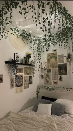 an unmade bed with plants hanging from the ceiling