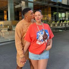 a man and woman standing next to each other in front of a large glass building