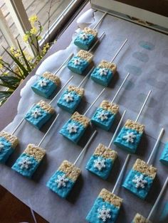 there are many blue and yellow cakes on the table with white frosted icing