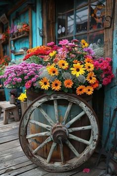 a wagon filled with lots of flowers sitting on top of a wooden floor next to a building