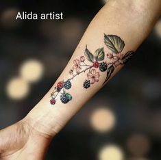 a woman's arm with flowers and berries on it