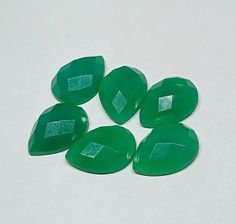 six green stones sitting on top of a white table