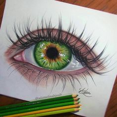 a drawing of an eye with colored pencils next to it