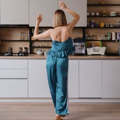 a woman standing in front of a kitchen counter with her hands up to the ceiling