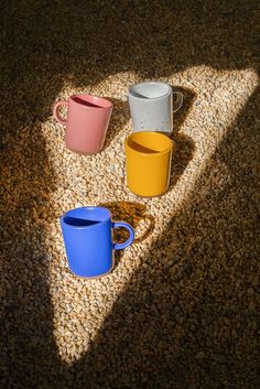 three different colored cups are sitting on the ground