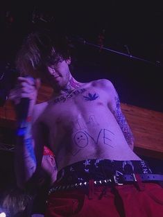 a man with tattoos on his chest holding a microphone