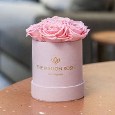 a pink rose in a round box sitting on a table with the logo of the million roses