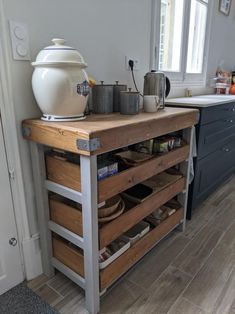 a kitchen island made out of wood and metal with drawers on the bottom, under a window