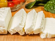 several pieces of cheese sitting on top of a wooden cutting board