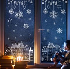 a young boy sitting in front of a window with snowflakes on it