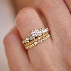 a woman's hand holding two gold rings with diamonds on top and bottom, in front of her